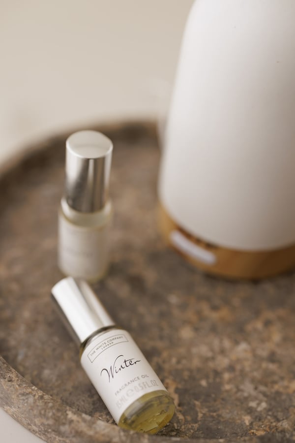 Two small spray bottles on a stone tray beside the diffuser, seen close in