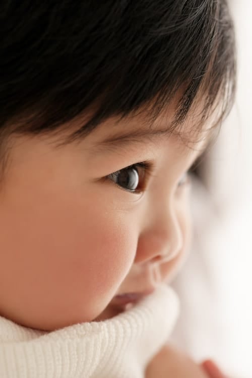 Profile of a baby with dark hair, looking away from the camera