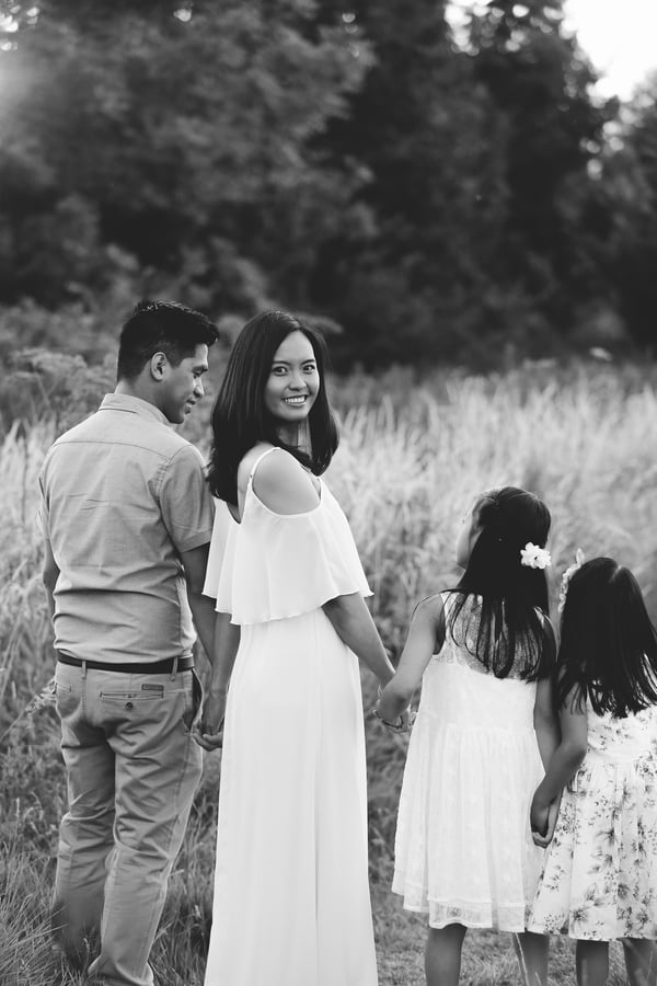 A family of five standing together in a summer meadow, the children in white dresses, in black and white