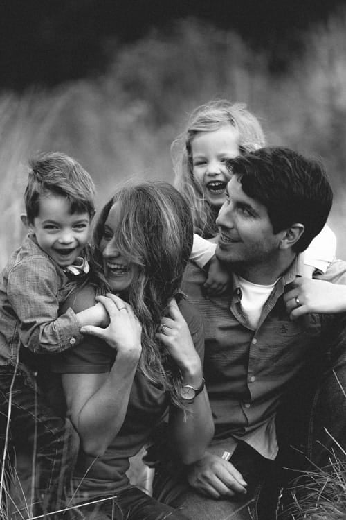Parents and two children laughing together in the grass