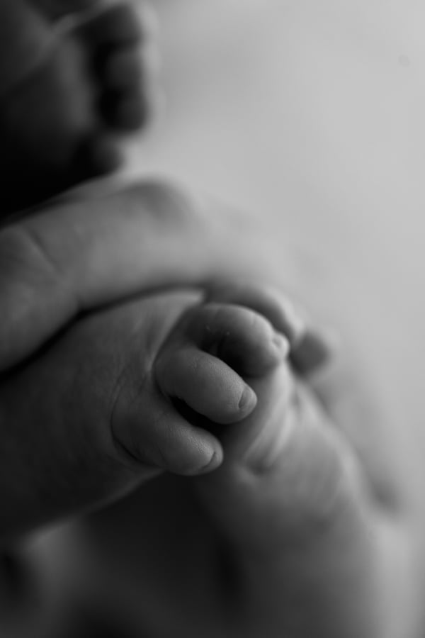 A newborn awake in a wrap on a white backdrop, in black and white