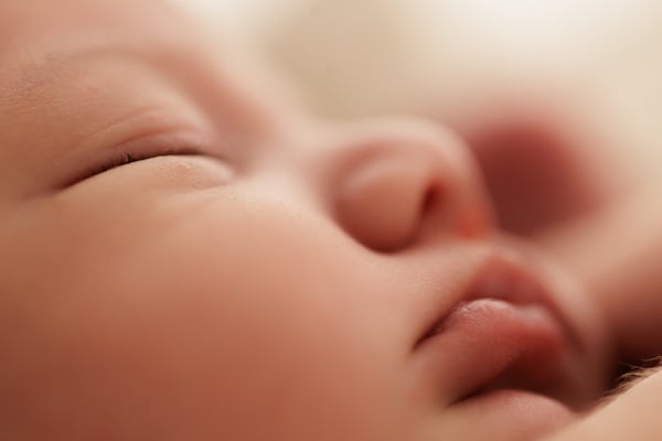 Extreme close-up of a sleeping newborn's closed eye, nose and lips