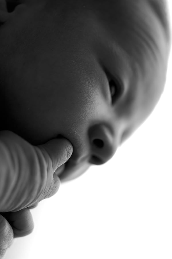 Close view of a newborn's face in low light, in black and white