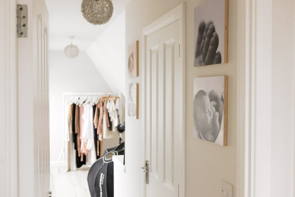 Looking down the hallway towards the rail of dresses, framed newborn portraits on the wall