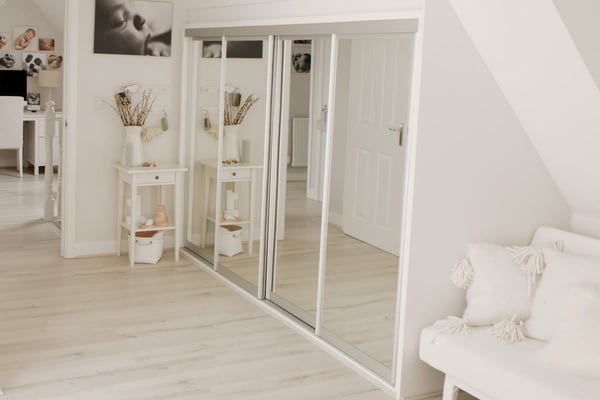 The studio landing: mirrored sliding doors, a console table with dried flowers, and framed newborn prints