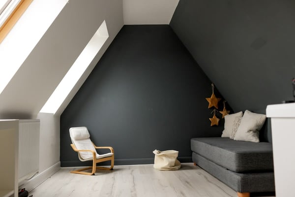 The sibling room: a charcoal wall, a small armchair, a low grey sofa and felt stars hanging
